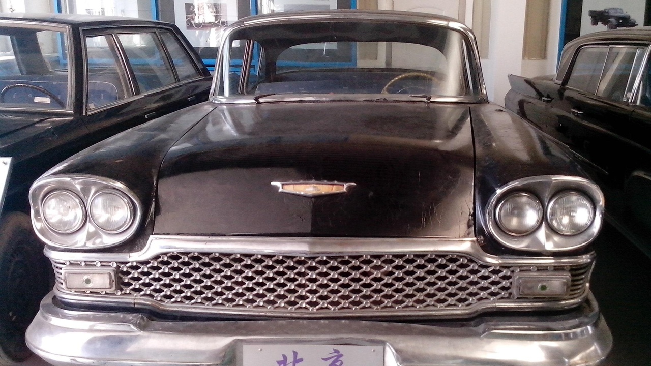 1962 Mercedes-Benz 220SE and Aston Martin DB4 parked outside a grand hotel.