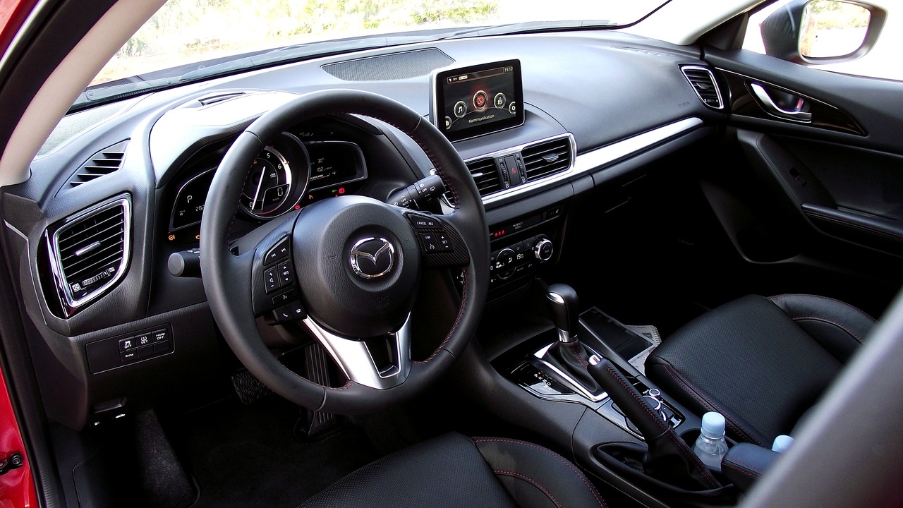 Driver using an automatic transmission shifter in a modern car interior.