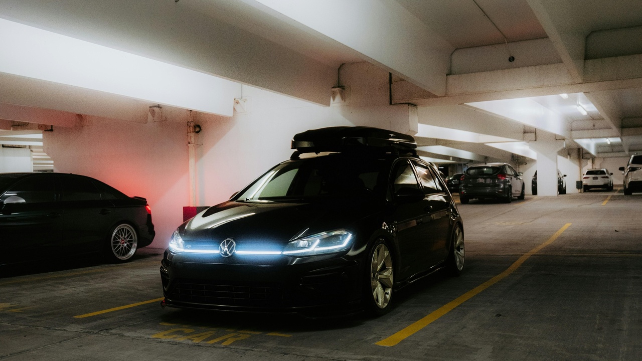 A car parked at a trailhead with a rooftop box and bikes mounted for a weekend adventure