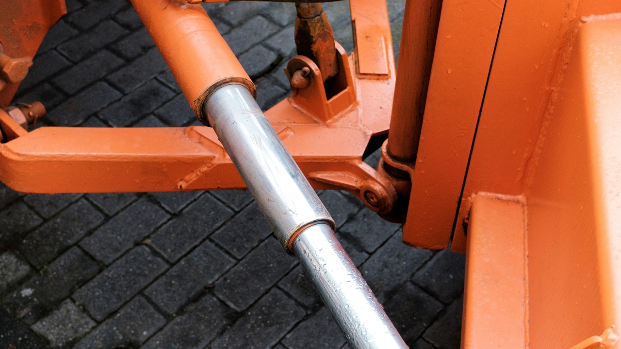 A metal strut brace linking the left and right shock towers in an engine bay, showing how the bar increases chassis rigidity