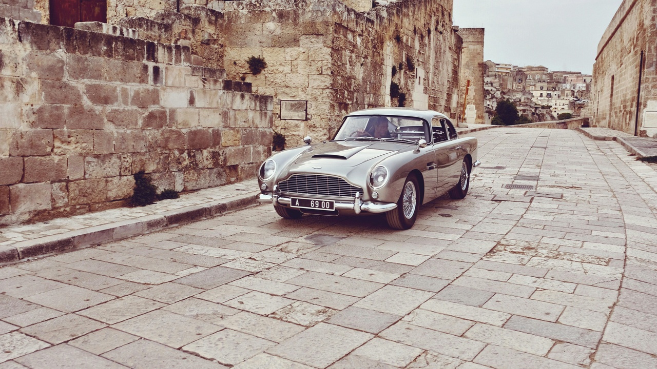Aston Martin DB5, Jaguar E-Type and Rolls-Royce Silver Cloud parked together showcasing British luxury design