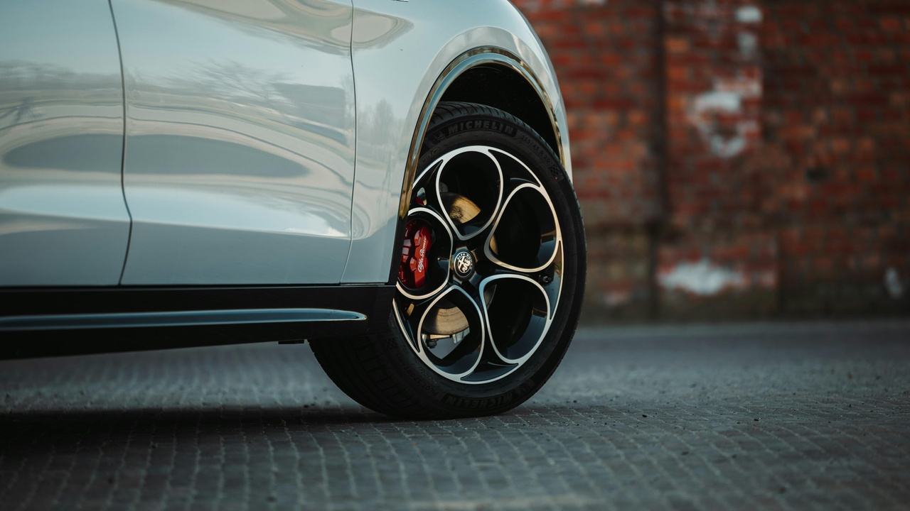 A parked Alfa Romeo Stelvio at a service center with technician nearby