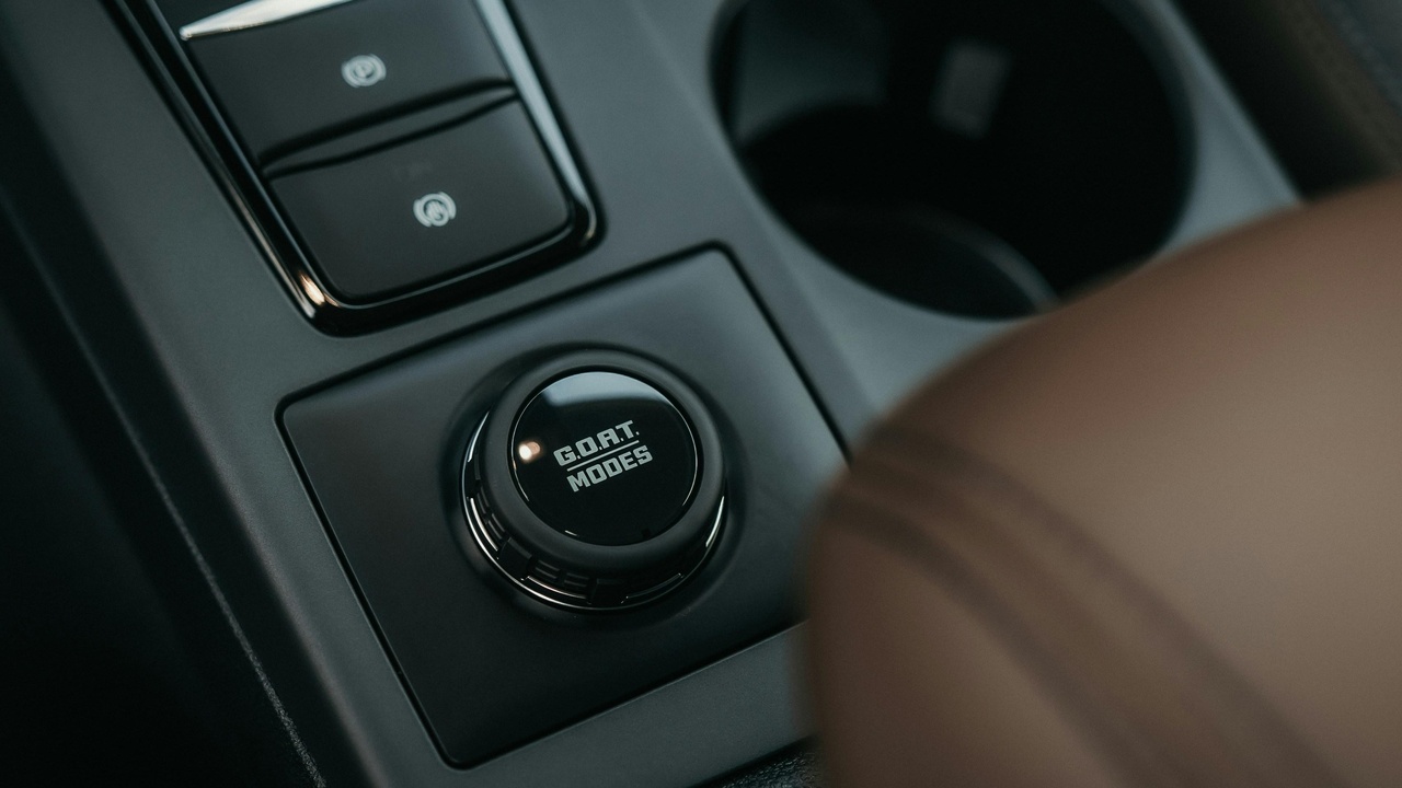 Driver pressing a push-button start on a modern car dashboard