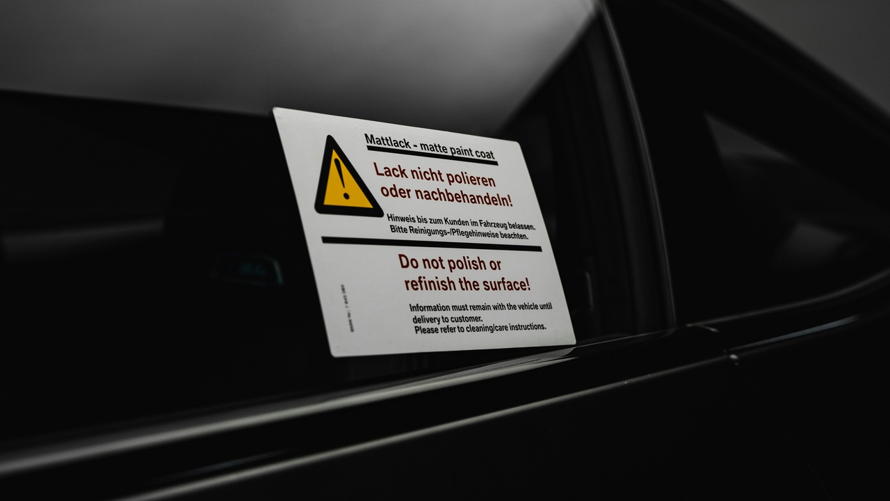 Car parked in a lot with visible alarm LED and security sticker indicating vehicle security and theft deterrence