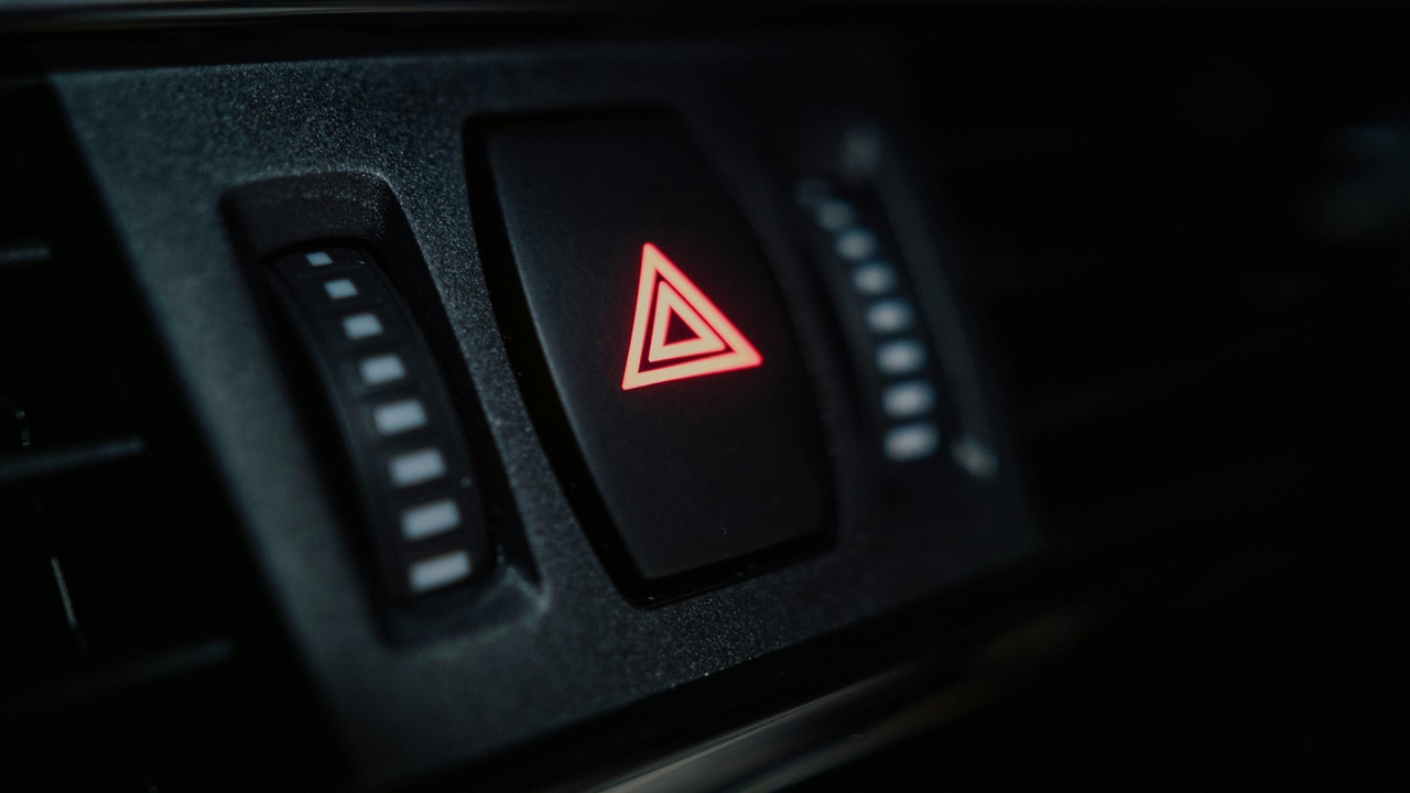 Person checking a smartphone alarm alert while standing near a parked car, implying occupant safety and intrusion alerts