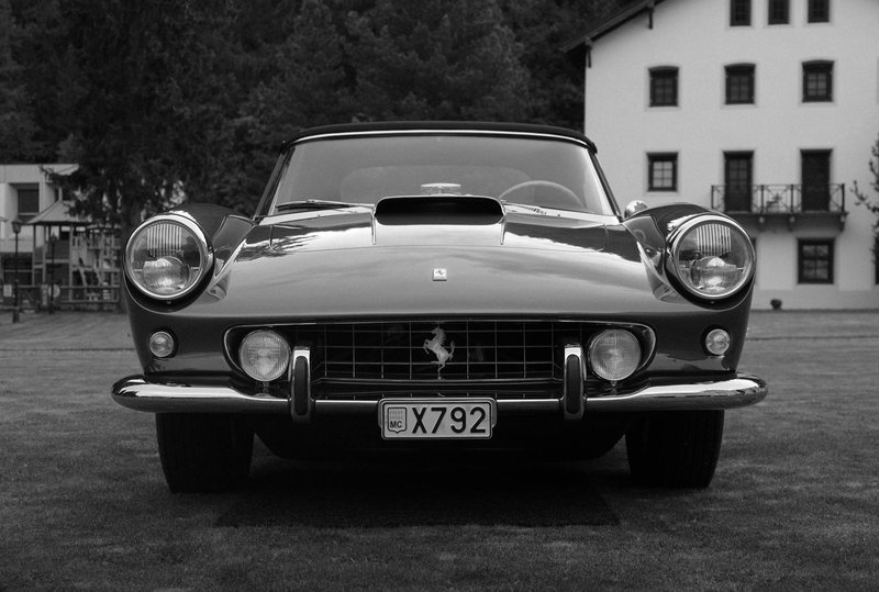 Elegant monochrome shot of a vintage Ferrari 250 GT parked outdoors, showcasing luxury and classic design.