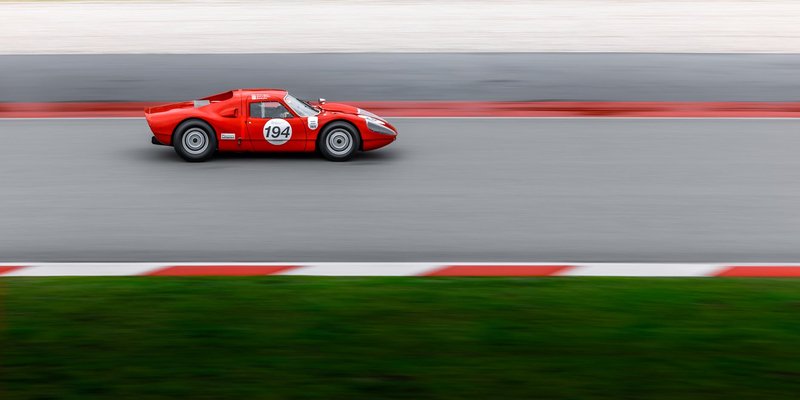 Red vintage race car speeding on a track with motion blur for dramatic effect.