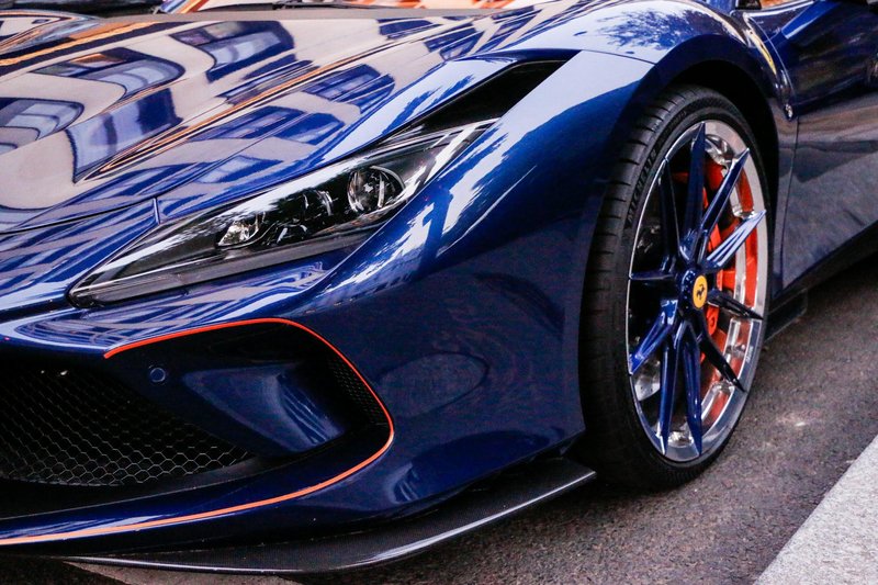 Close-up of a sleek blue sports car with shiny reflective surface and unique wheel design.