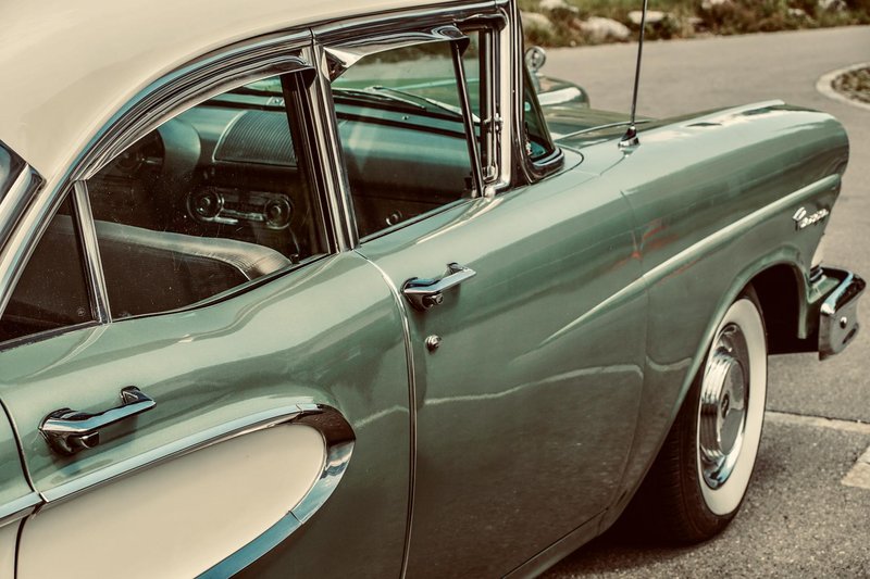 Close-up view of a green vintage classic car exterior, showcasing its sleek design and retro details.