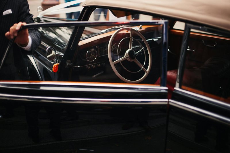 Close-up of an elegant vintage car interior, highlighting its classic steering wheel and luxurious details.