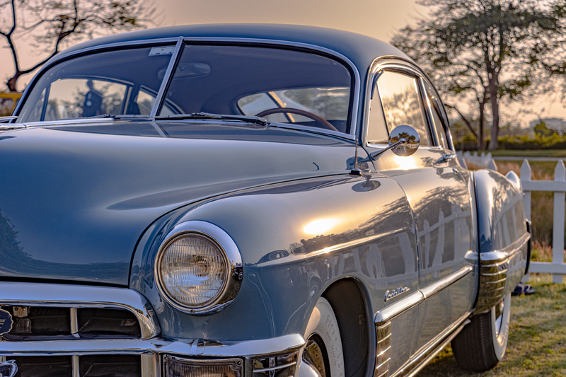 Closeup of a vintage 1950 Cadillac Series 62 coupe in a serene outdoor setting during sunset.