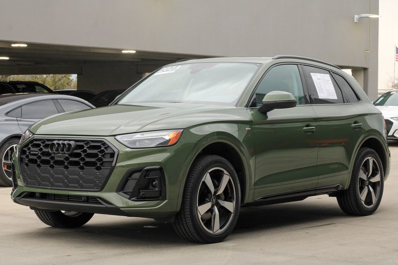 Modern khaki green 2024 Audi Q5 SUV parked in an urban parking lot, showcasing sleek automotive design.