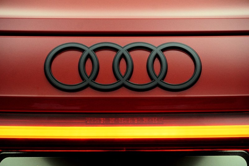 A detailed close-up of the Audi logo on a bright red vehicle, highlighting its design.