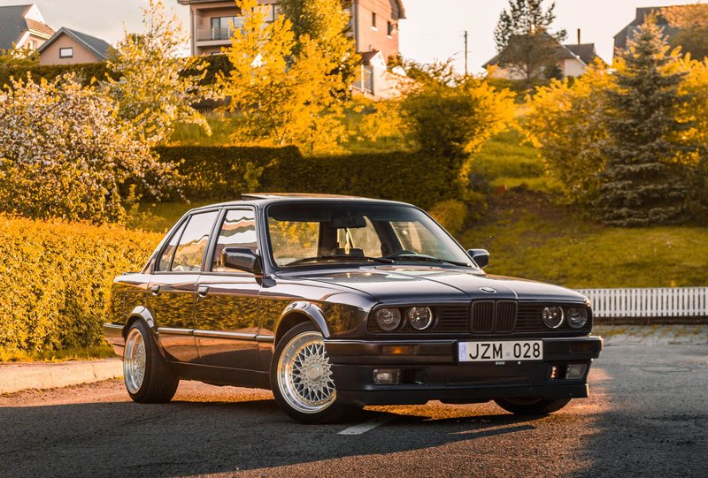 Vintage BMW E30 parked on a sunny suburban street, capturing the classic sedan's retro charm.