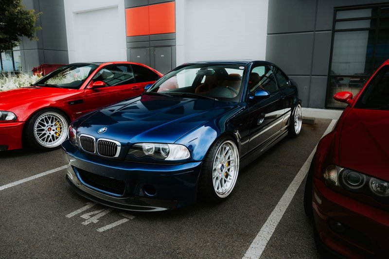 A sleek blue sports car parked outdoors alongside other vehicles, showcasing modern automotive design.