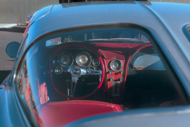 Capture of a vintage Chevrolet Corvette's luxurious red leather interior and glossy steering wheel.
