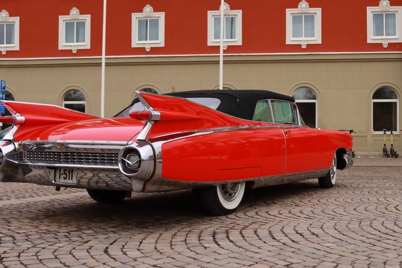 Classic red Cadillac parked on cobblestone street in Jönköping, Sweden showcasing vintage automotive design.
