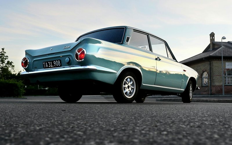 Low angle shot of a vintage Ford car parked on a city street during sunset.