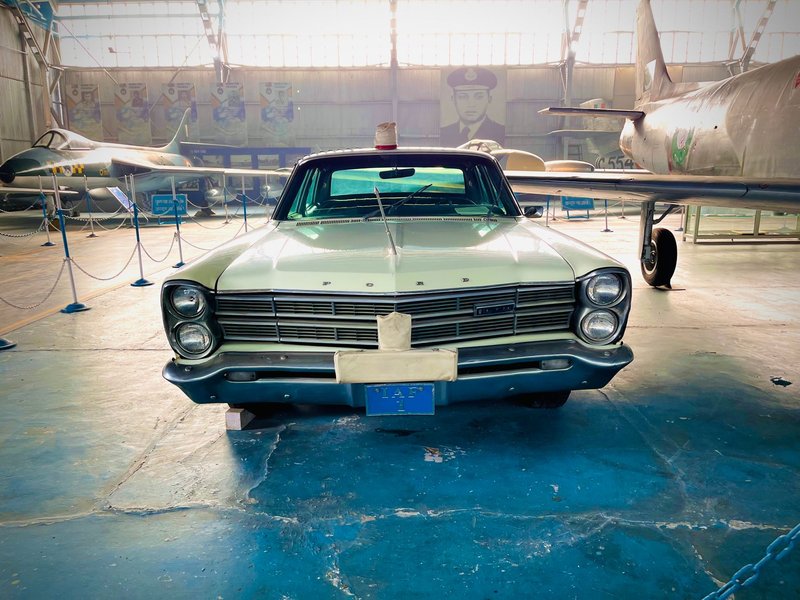 Front view of a vintage Ford car showcased in an indoor aviation museum setting.
