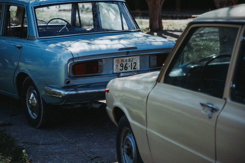 Close-up of vintage cars with Japanese license plates, parked outdoors.