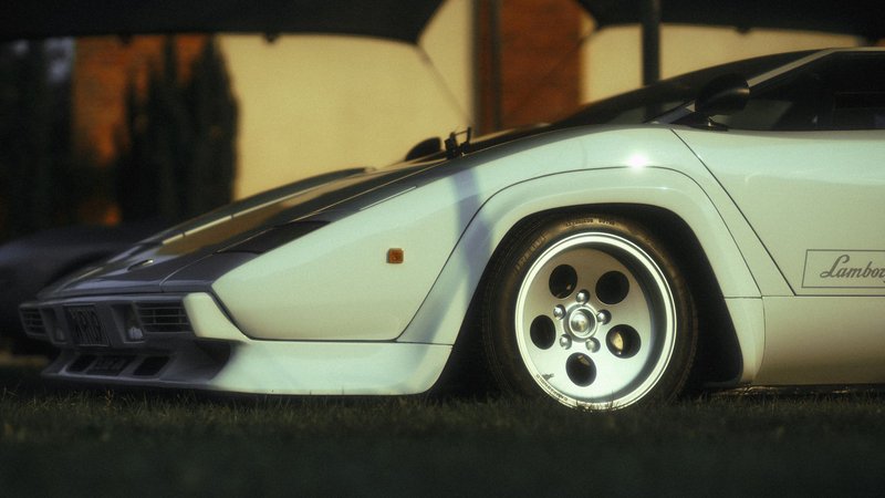 Close-up of a classic Lamborghini sports car, showcasing its sleek details and design in warm evening light.
