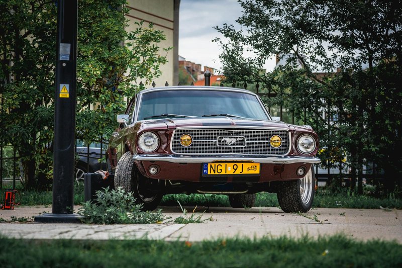 Front view of a vintage red Ford Mustang parked outdoors, showcasing its classic design