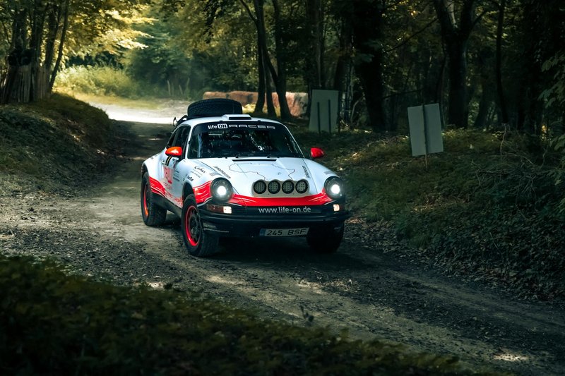 Vintage rally car driving through a scenic forest path in Southampton, UK.