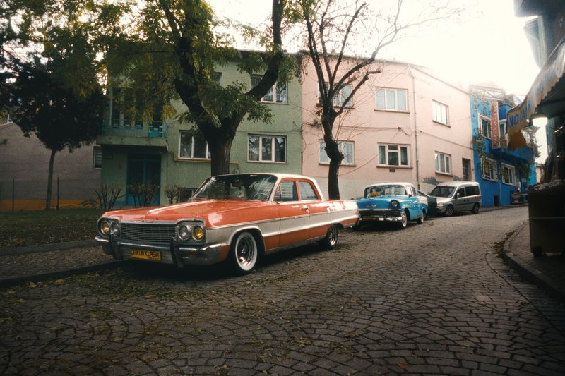 Vintage Chevrolet car parked on a cobblestone street in an urban neighborhood.