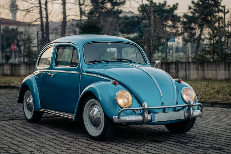 Classic blue Volkswagen Beetle parked outdoors on a cloudy day, showcasing vintage charm.