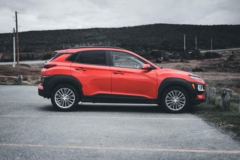 Red SUV parked outdoors on a cloudy day, showcasing sleek design and vibrant color.