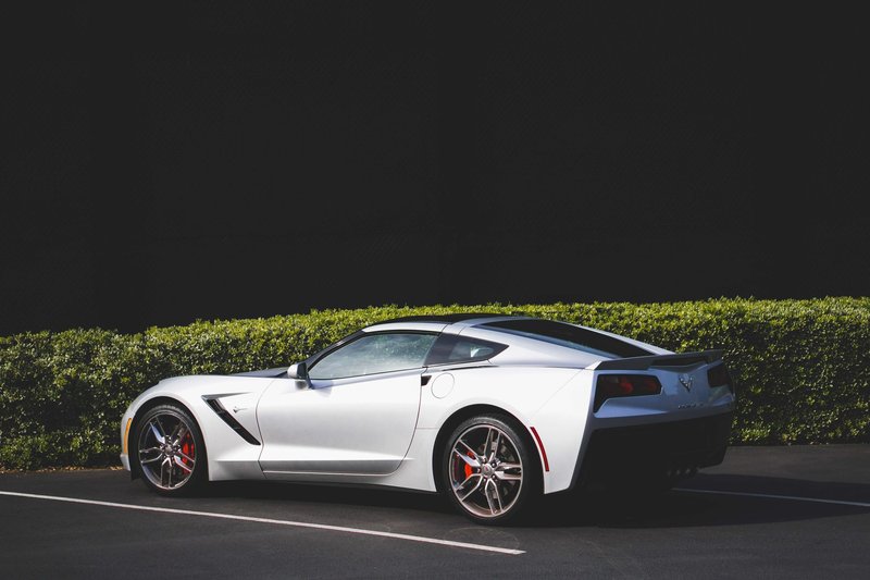 Side view of a luxury silver Corvette sports car parked outdoors.