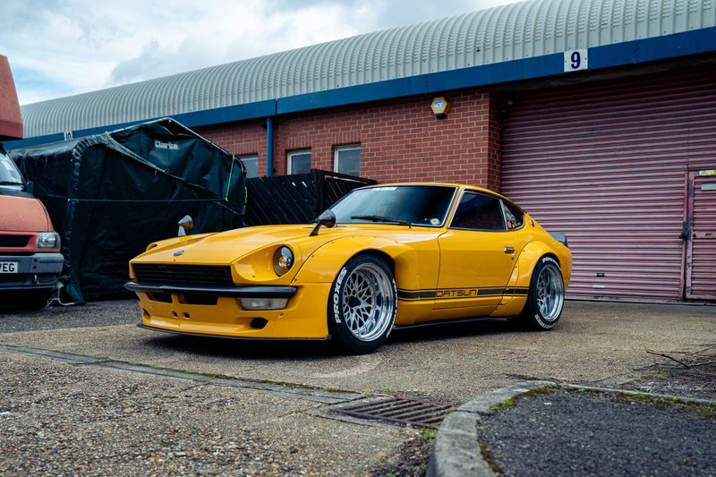 Vintage yellow Datsun 240Z parked outside a garage in Southampton, UK, showcasing automotive classic style.
