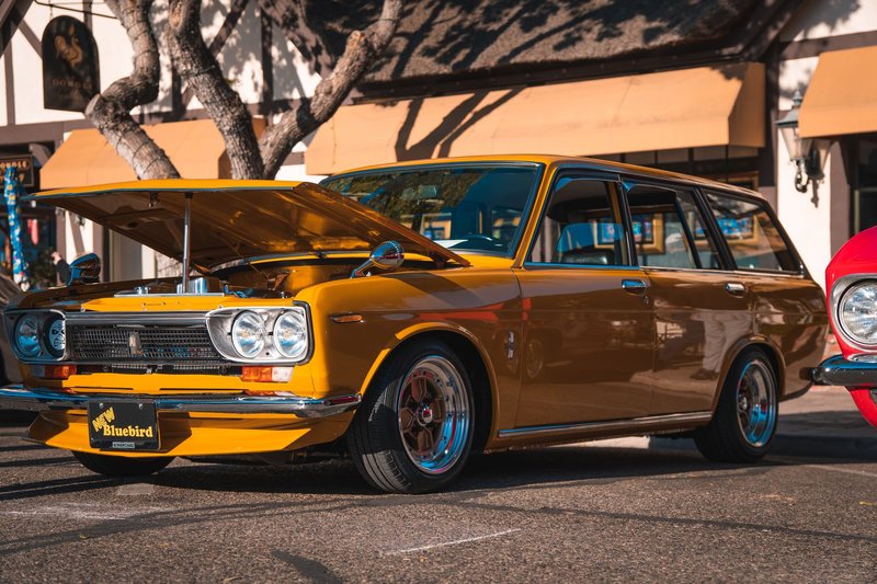 Captured in Solvang, CA, a vintage yellow Datsun 510 station wagon gleams under the sun.