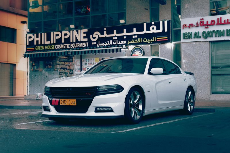 White Dodge Charger parked in front of Philippine store in Abu Dhabi.