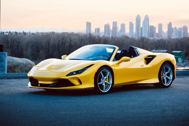 Luxury yellow sports car parked against a city skyline at sunset, showcasing elegance and speed.