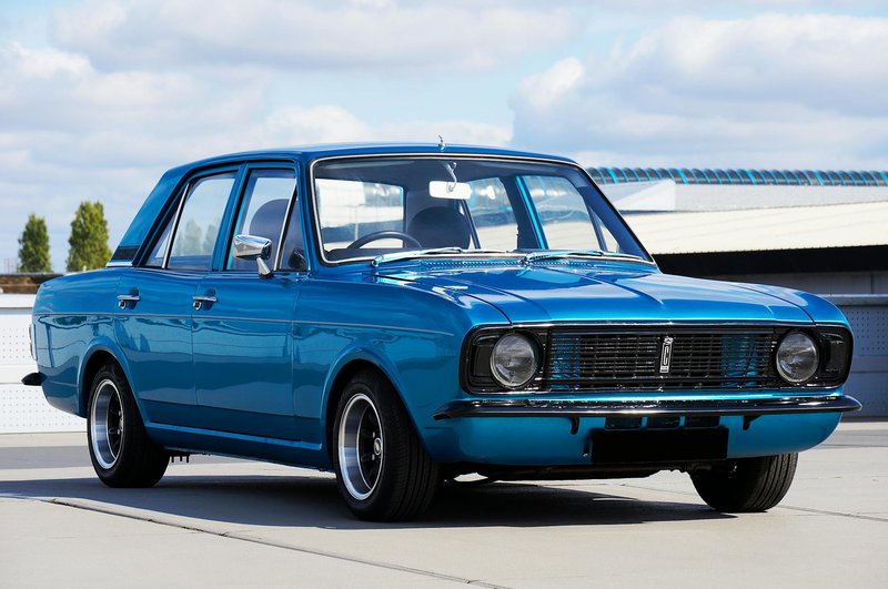 A beautifully restored vintage blue Ford Cortina parked outdoors on a sunny day, showcasing classic design.