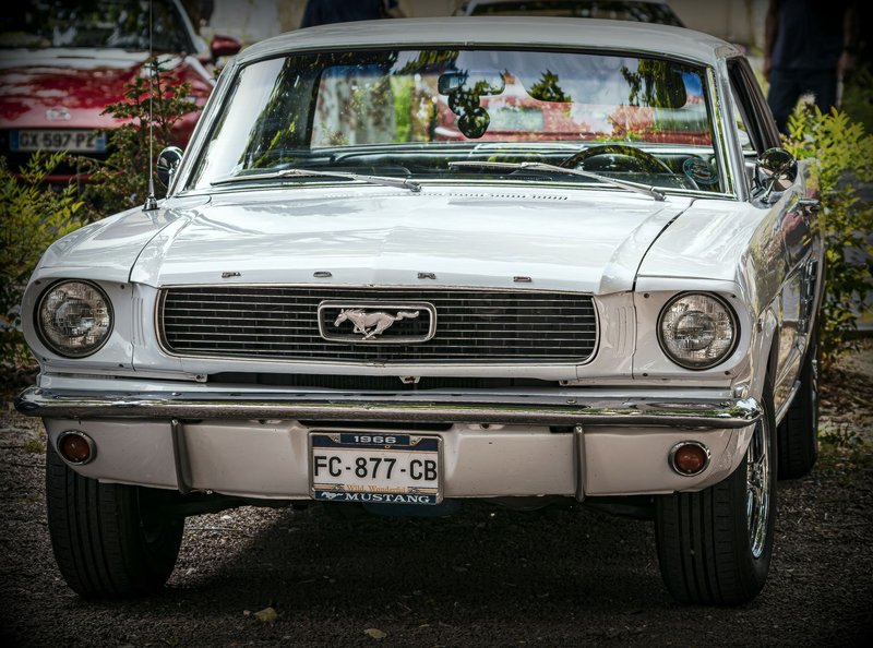 Front view of a classic white 1966 Ford Mustang, showcasing its iconic design in an outdoor setting.