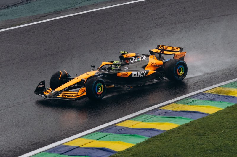 A vibrant Formula One car speeding on a wet track, showcasing dynamic motorsport action.
