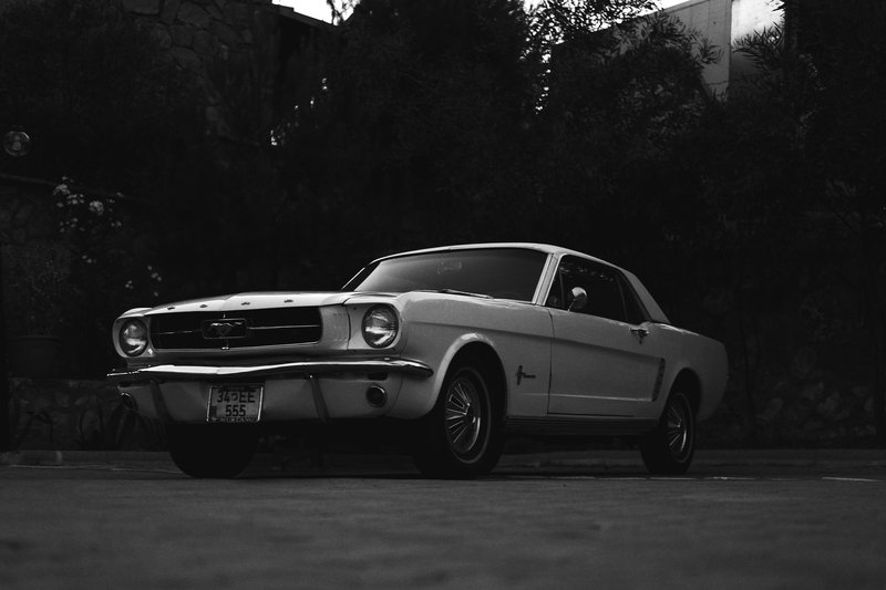 A vintage Ford Mustang car parked in a dark, atmospheric outdoor setting.