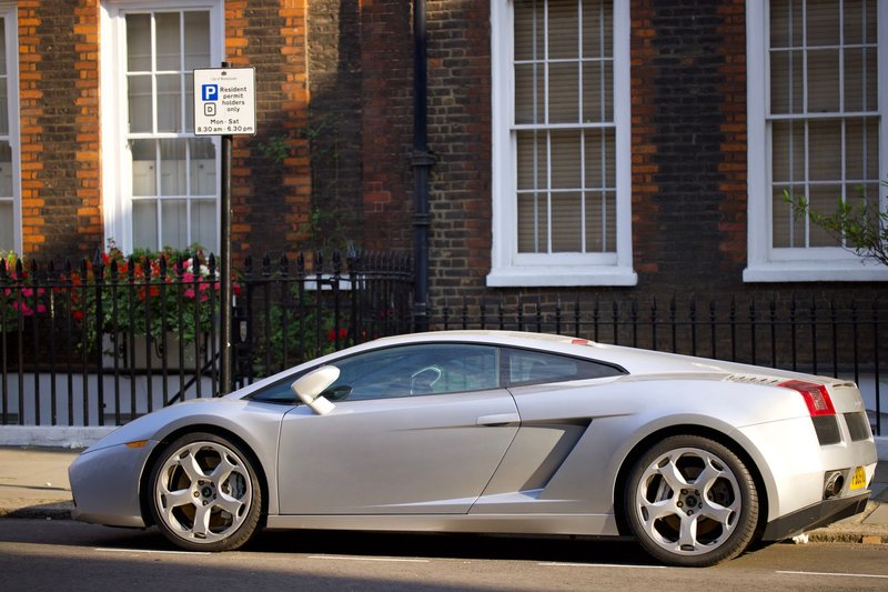 Silver Lamborghini parked in a charming city street captures luxury lifestyle.