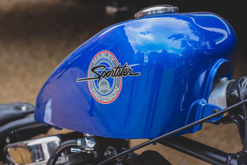 Vibrant blue Harley Davidson Sportster gas tank with shiny chrome details.