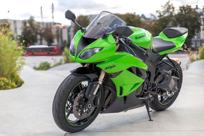 A sleek green Kawasaki Ninja motorcycle parked in an urban setting during the day.