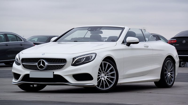 Elegant white Mercedes-Benz convertible parked outdoors, showcasing luxury and style.