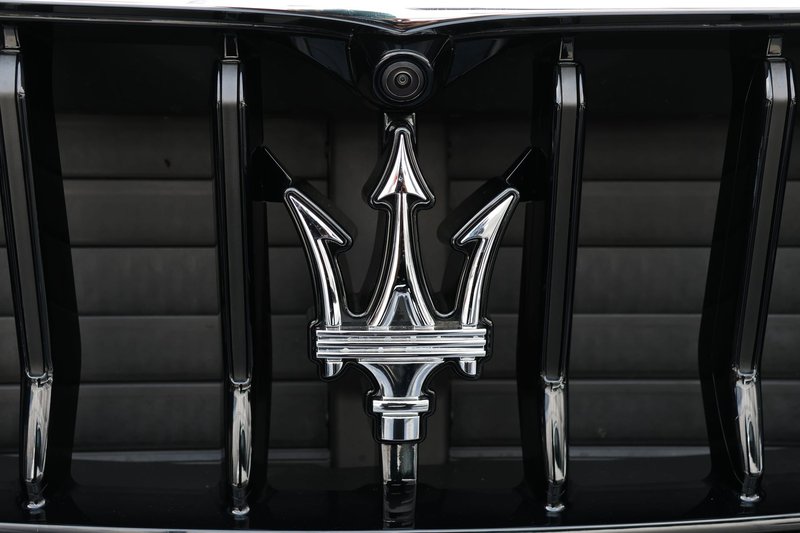 Close-up of Maserati car grill featuring the iconic trident emblem showcasing luxury and elegance.