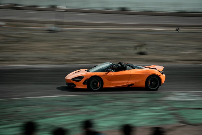 Orange supercar speeding on a race track in Colorado, showcasing automotive excellence.