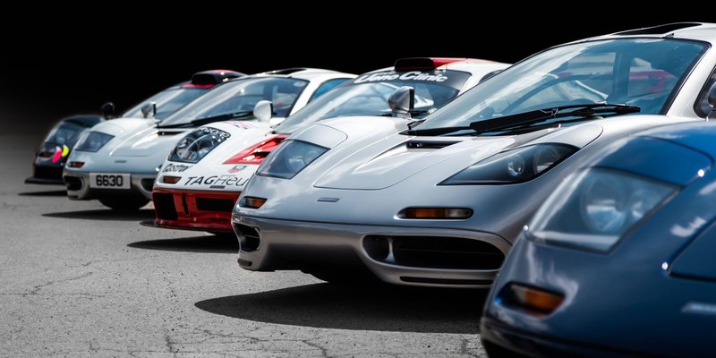 A dynamic lineup of various classic and modern supercars captured in perfect lighting.