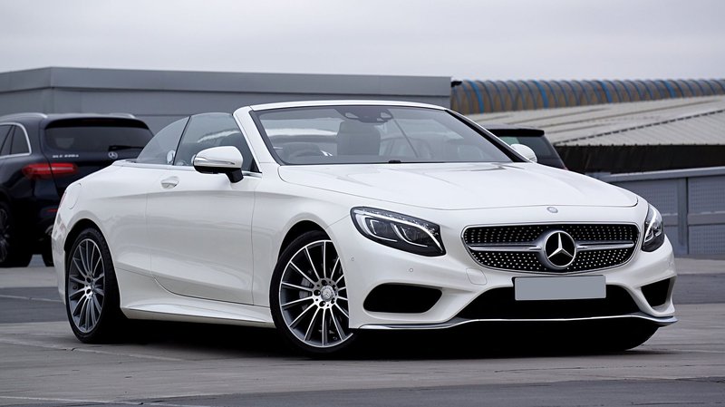 Elegant white Mercedes-Benz convertible in a parking lot, exuding luxury and style.