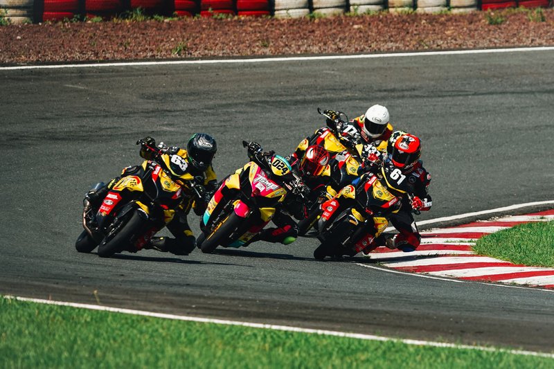 Dynamic shot of four motorcyclists racing on a curved track, showcasing speed and competition.