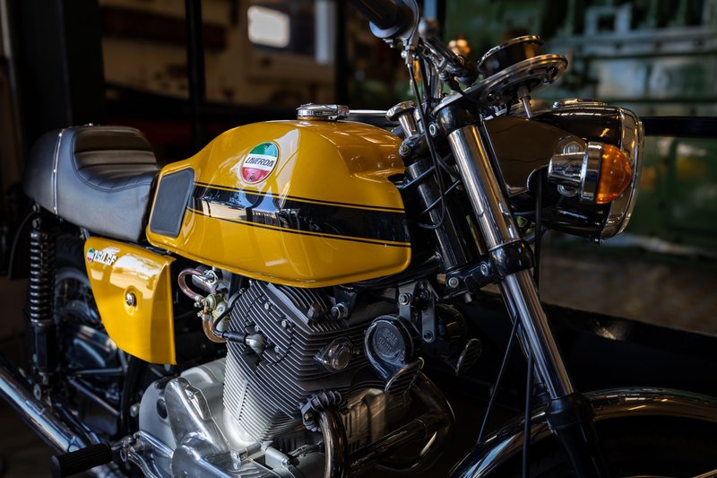 Close-up of a vintage yellow Laverda motorcycle indoors, showcasing its engine and design.