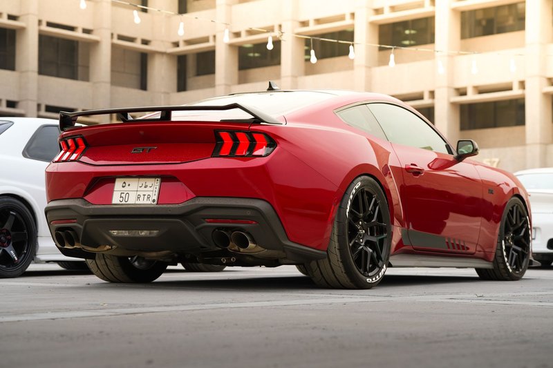 Red Ford Mustang GT parked in Al Khobar, Saudi Arabia, showcasing sleek design and power.
